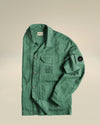 Green crinkled utility jacket by Alessi, with 'C.P. Company ALESSI' on a chest pocket, button-front, and a black 'C.P. Company' sleeve badge.
